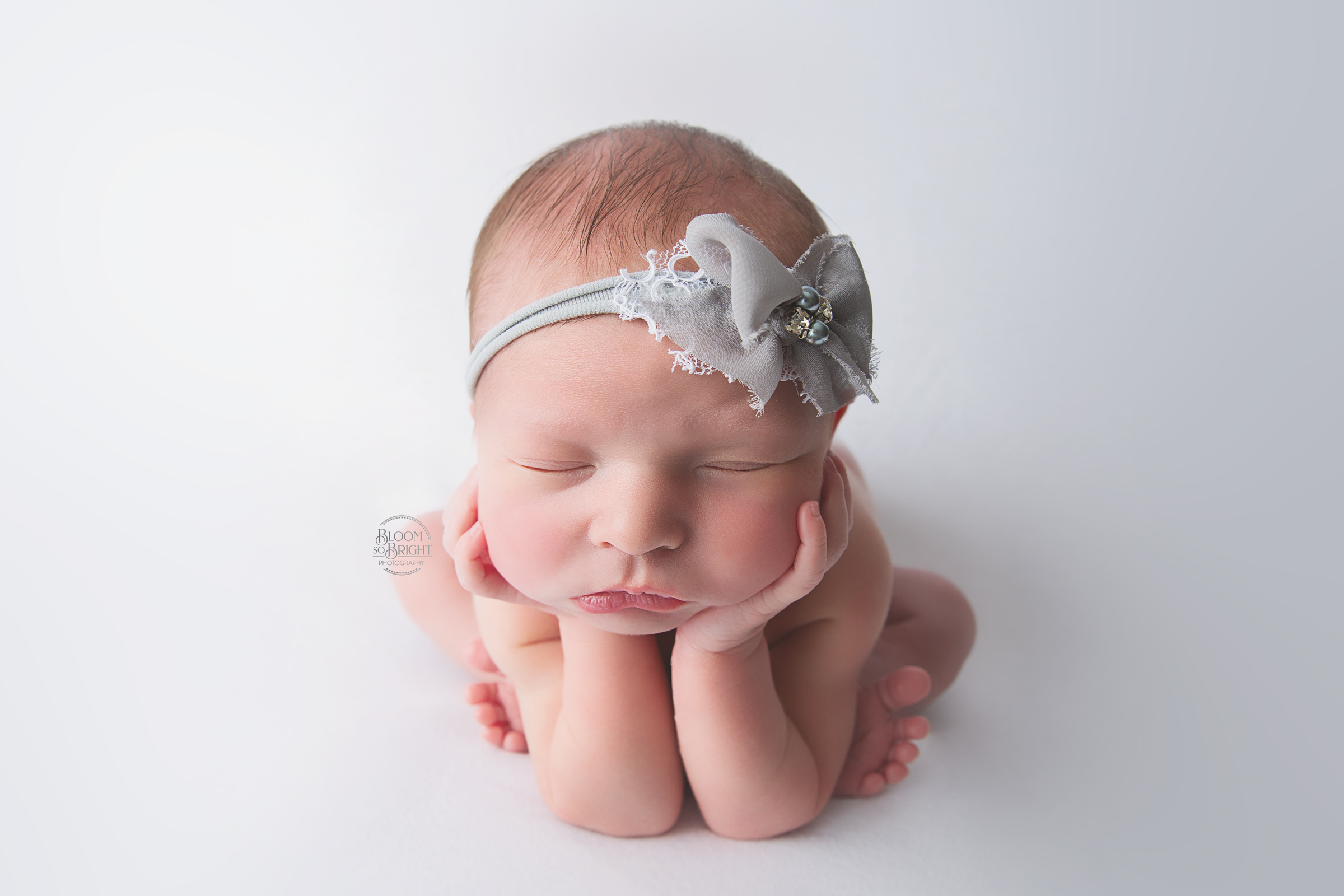 Newborn with a gray bow in a frog pose